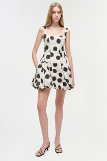 White sleeveless mini dress with black polka dot pattern and gathered skirt.