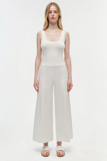 Woman wearing a white sleeveless tank top and off-white cotton cropped pants with a wide-leg silhouette.