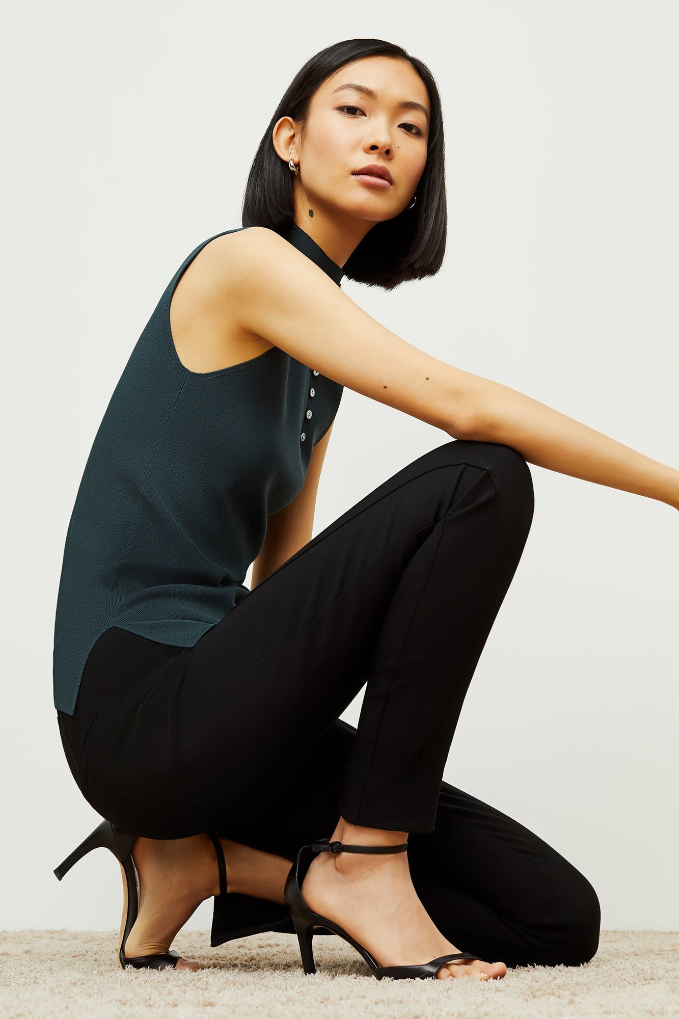Side image of a woman standing wearing the curie pant in black | Exclude