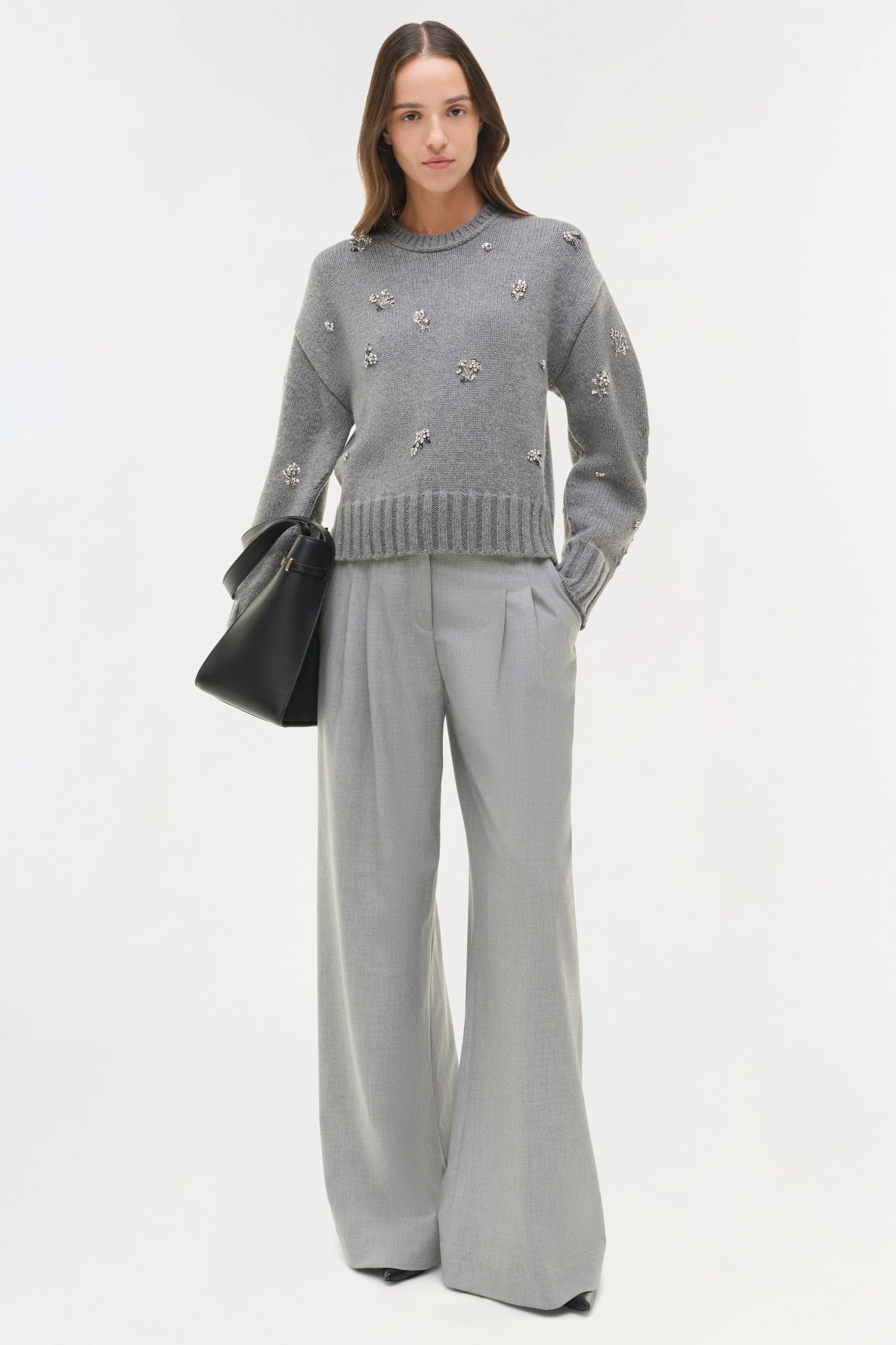 Gray crewneck knit sweater with scattered crystal embellishments worn with matching gray trousers.