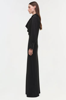 Black satin gown with draped side detail and long sleeves, shown on model in profile.