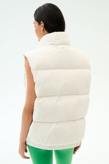 A woman is shown from the back wearing the SPLITS59 Summit Nylon Puffer Vest in white and green pants against a plain backgroundâ€”an ideal lightweight layer for cool weather workouts.