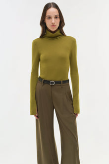 Khaki wide-leg pants with pleated front and belt, styled with olive turtleneck.