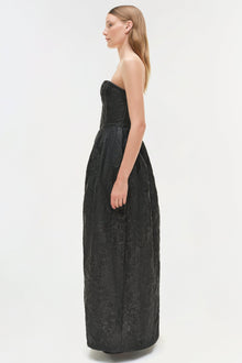 Woman wearing a black jacquard strapless gown with textured patterned fabric and fitted bodice.