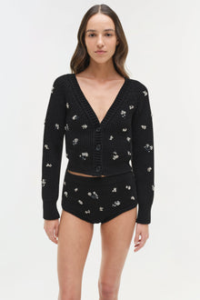 Black ribbed knit cardigan with silver floral embellishments and button front closure.