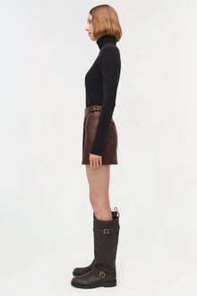 Brown leather mini skirt with buckle waistband detail, worn with black turtleneck.