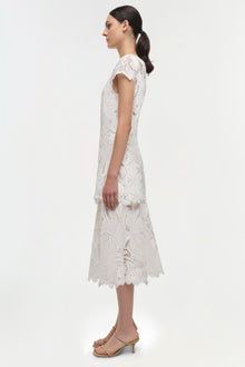 White lace midi dress with short cap sleeves and scalloped hem, shown on model in profile view.