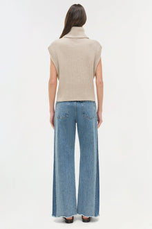Blue straight leg jeans with frayed hem, shown from behind with cream sleeveless turtleneck.
