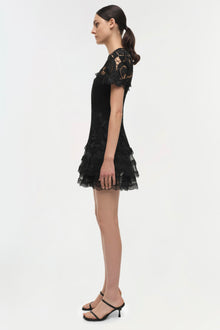 Black lace short dress with short sleeves and tiered lace hem, shown on model in profile view.