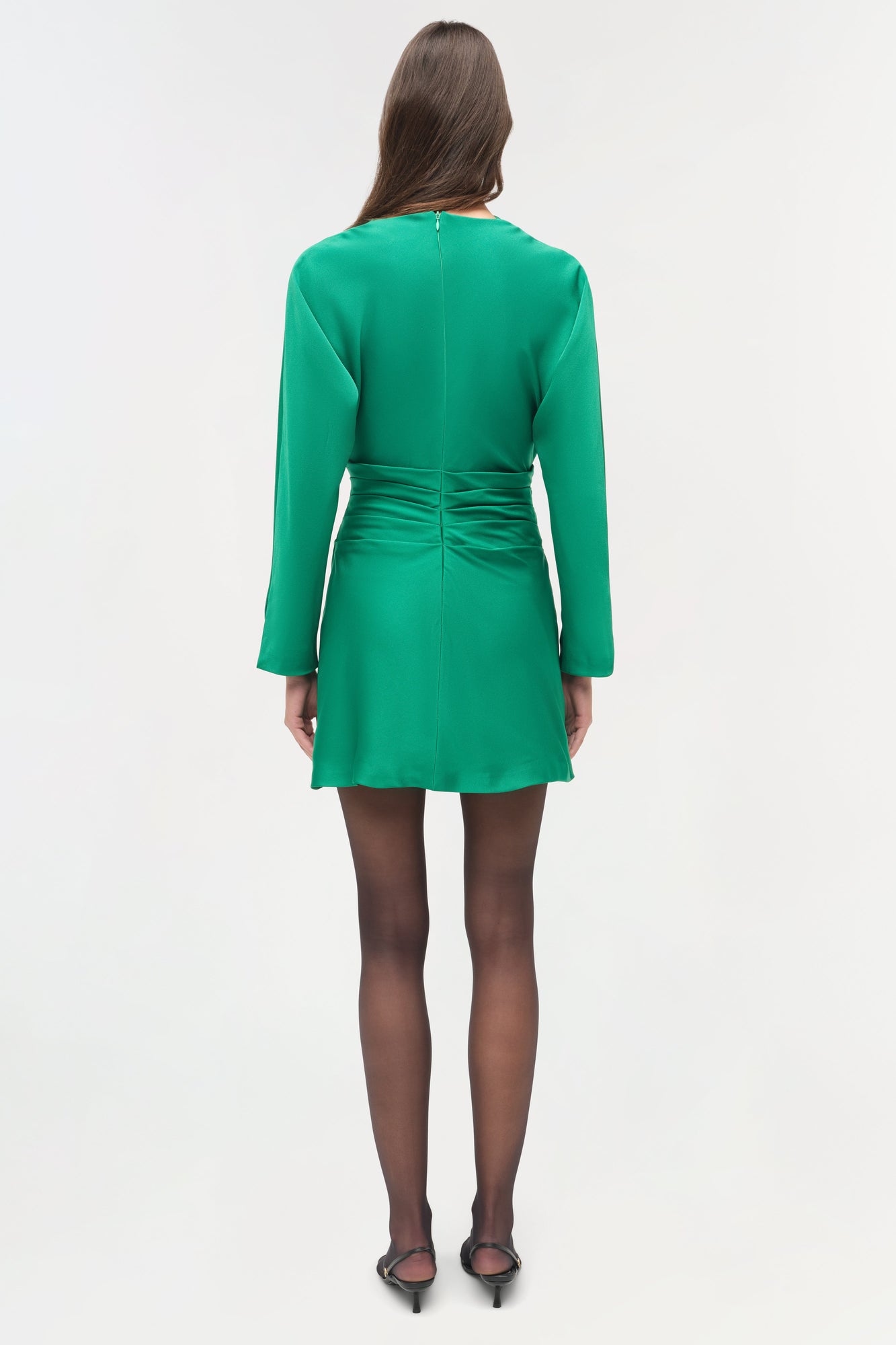 Green satin mini dress with long sleeves and ruched waist detail, shown from back view on model.