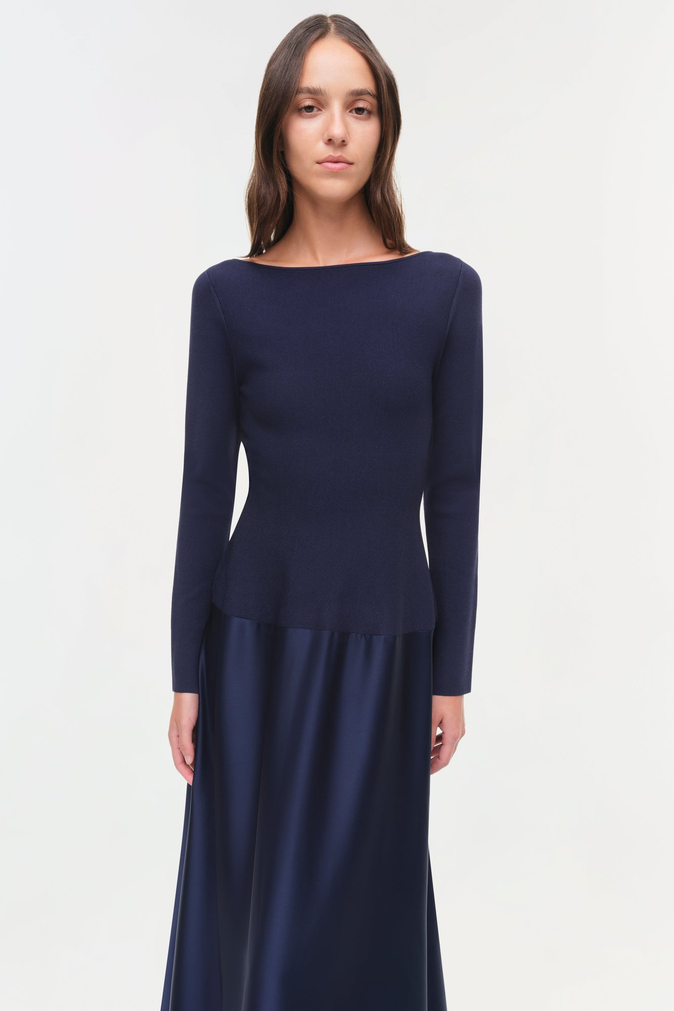 Navy long-sleeve gown with round neckline and satin skirt panel at hip.