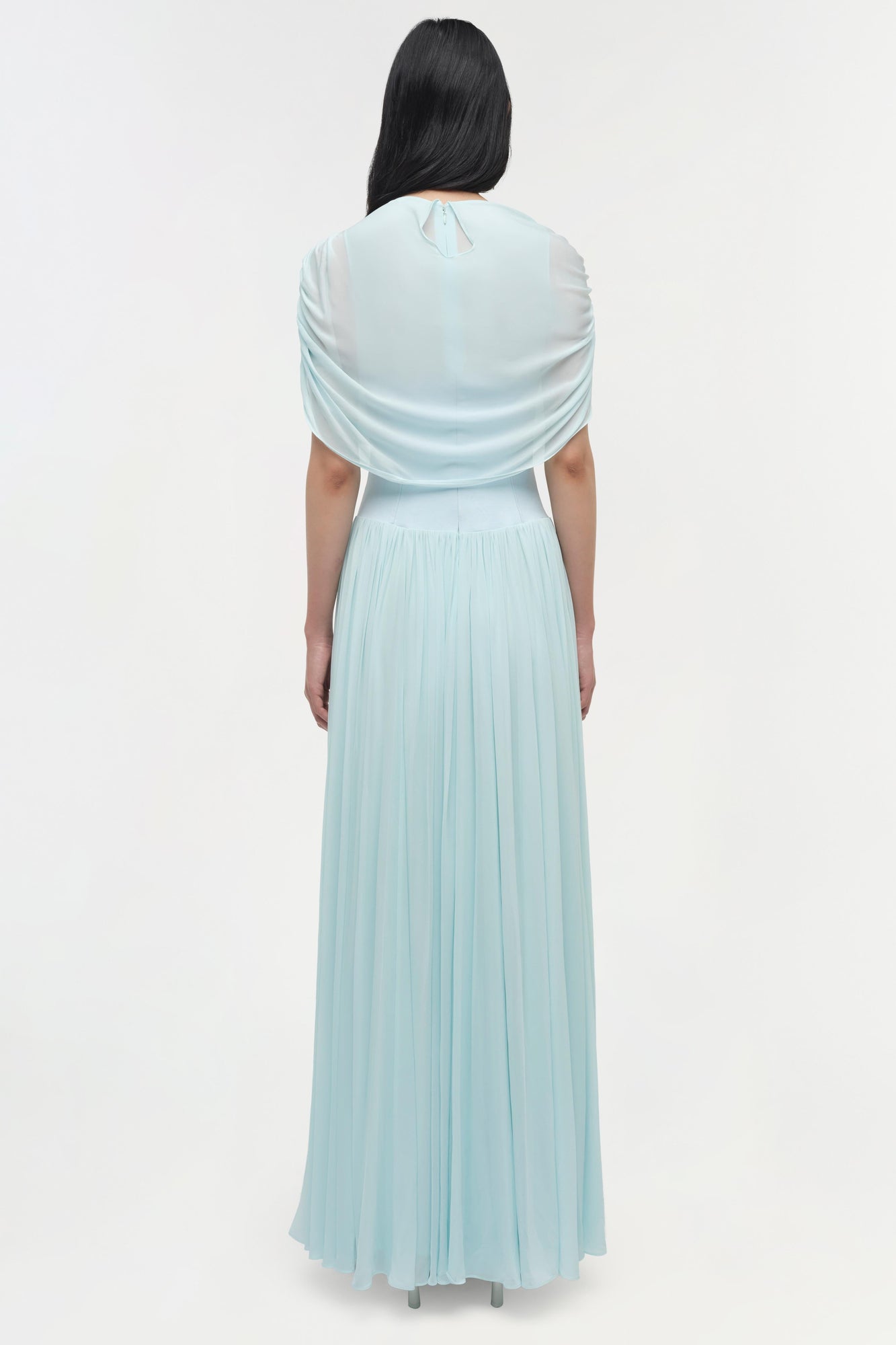 Light blue maxi dress with draped cape overlay and pleated skirt, shown from back view.