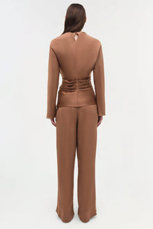 Woman wearing tan satin wide-leg pants with a matching long-sleeve cropped top, shown from back view.