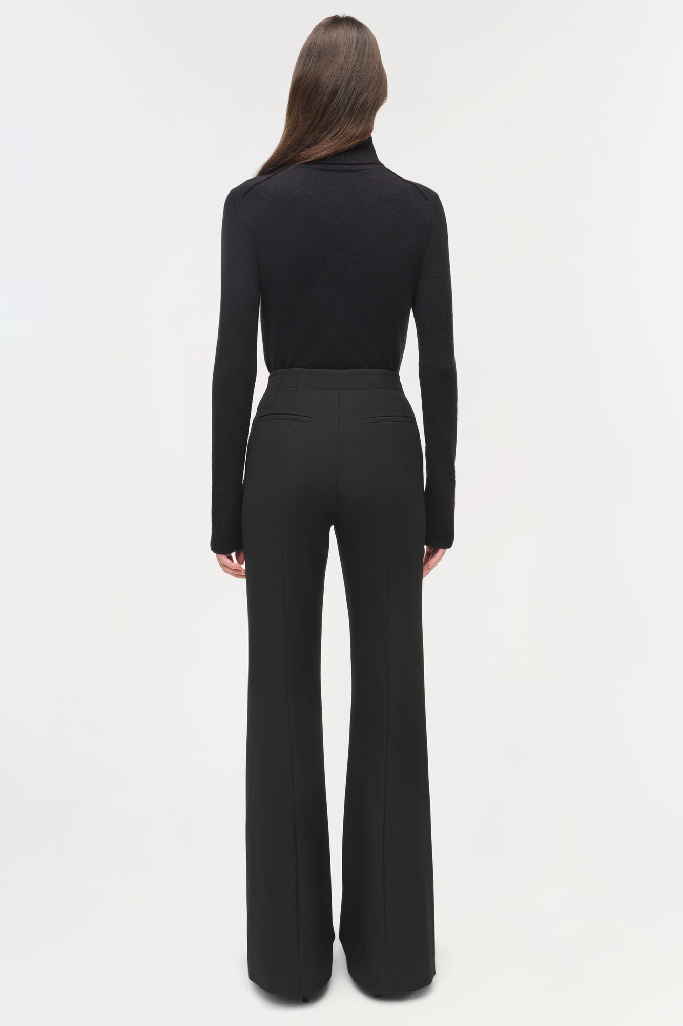 Black tailored trousers with flared legs and back pockets, worn with black turtleneck.