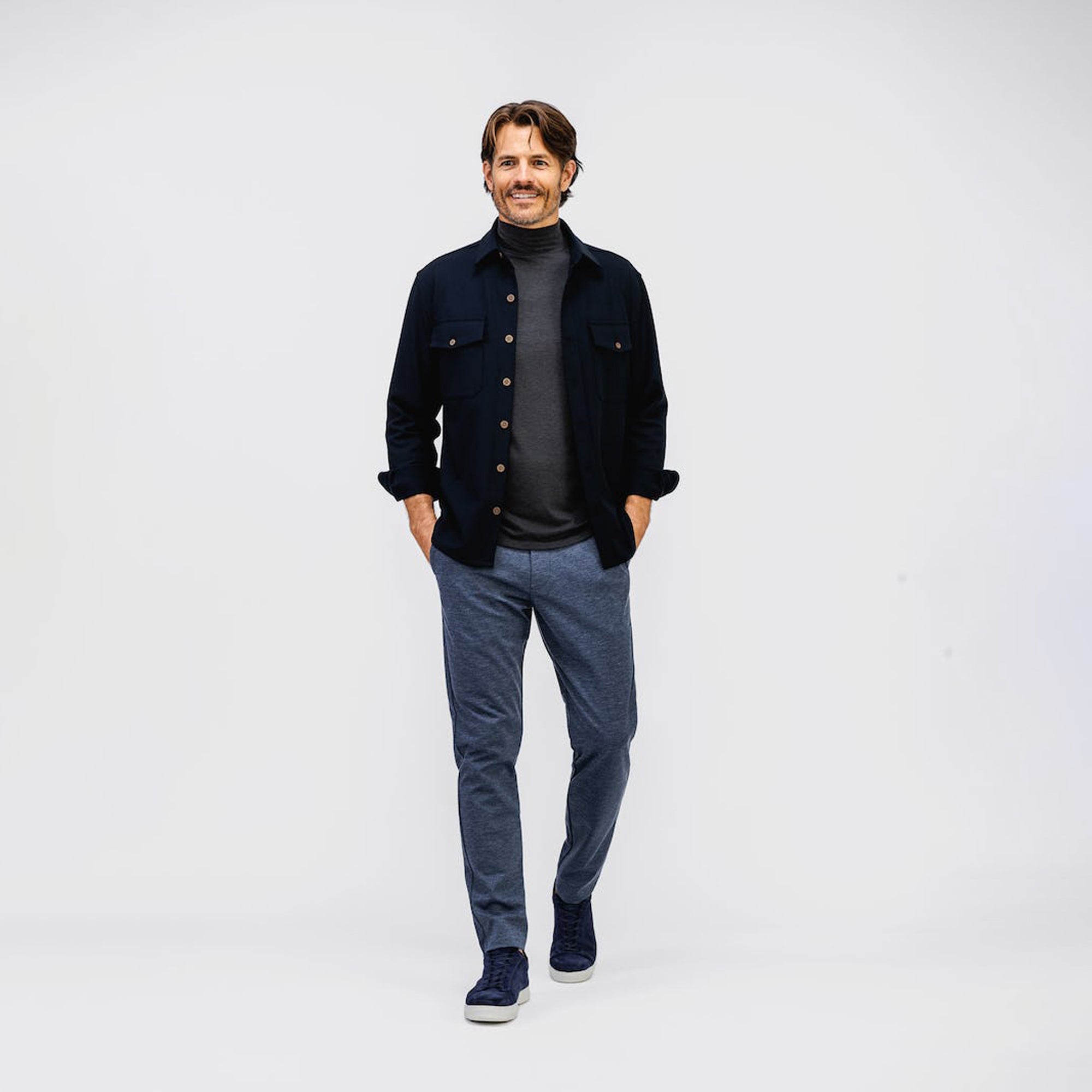 model wearing mens fusion overshirt navy and mens fusion jogger navy heather and mens composite merino mock enck charcoal heather full body both hands in pocket