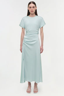 Light blue satin midi dress with short sleeves, ruched side detailing, and curved neckline on model wearing white sandals.