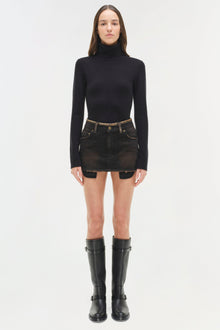 Black denim mini skirt with distressed details and button waistband, styled with black turtleneck and boots.