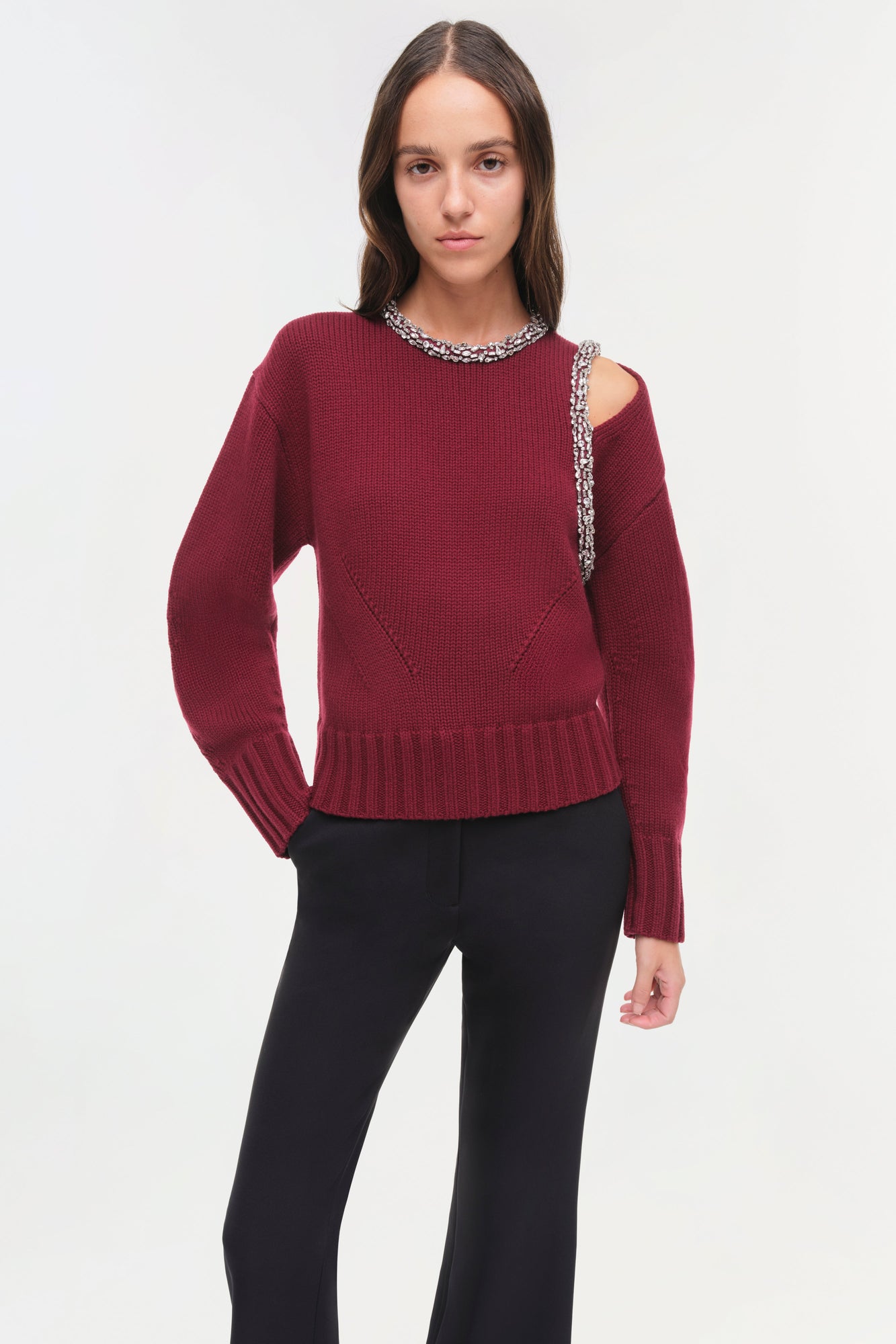 Burgundy ribbed pullover with crystal beading at neckline and shoulder cutout, paired with black pants.