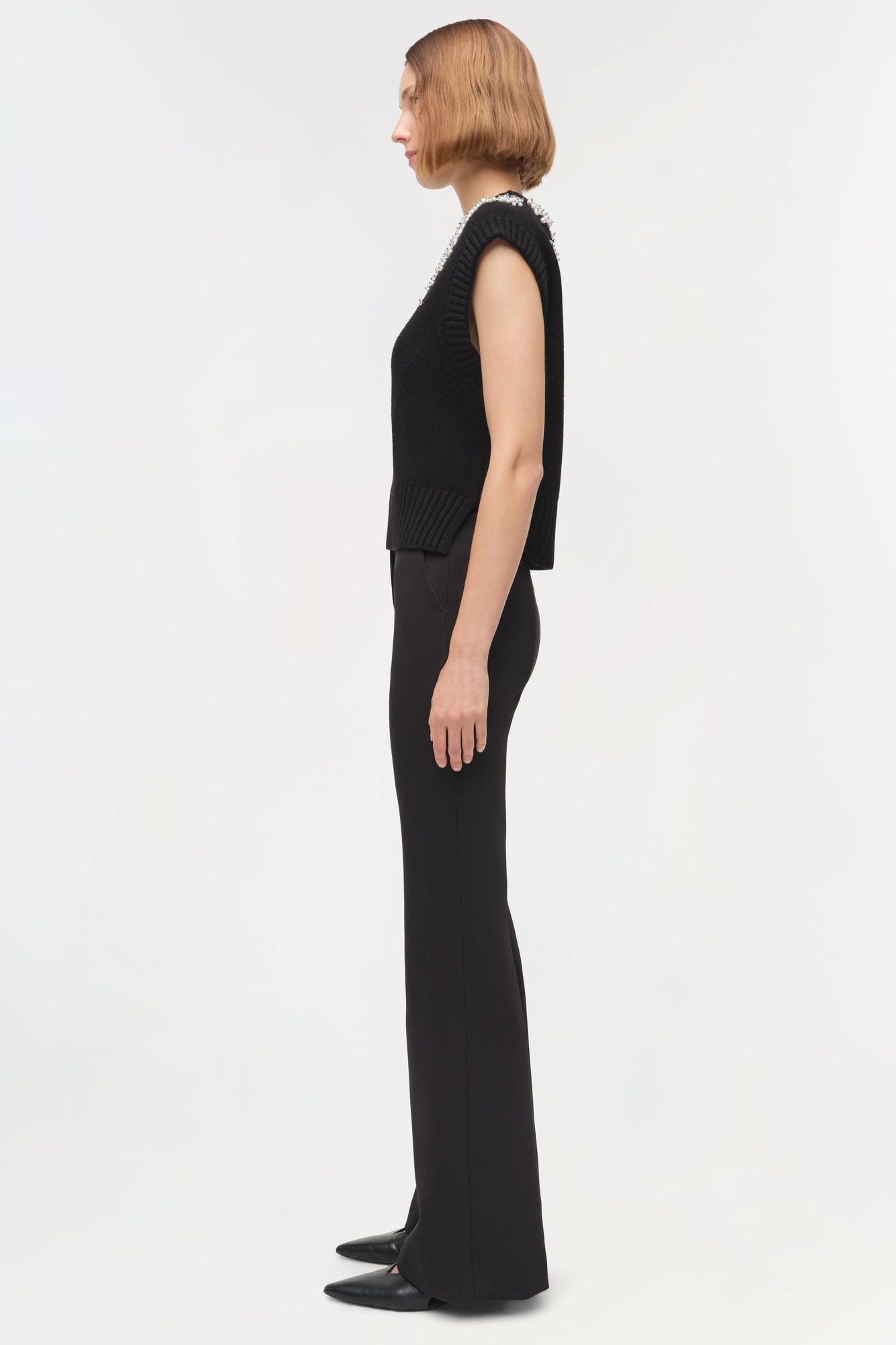 Black sleeveless knit vest with embellished neckline, worn with matching knit pants.