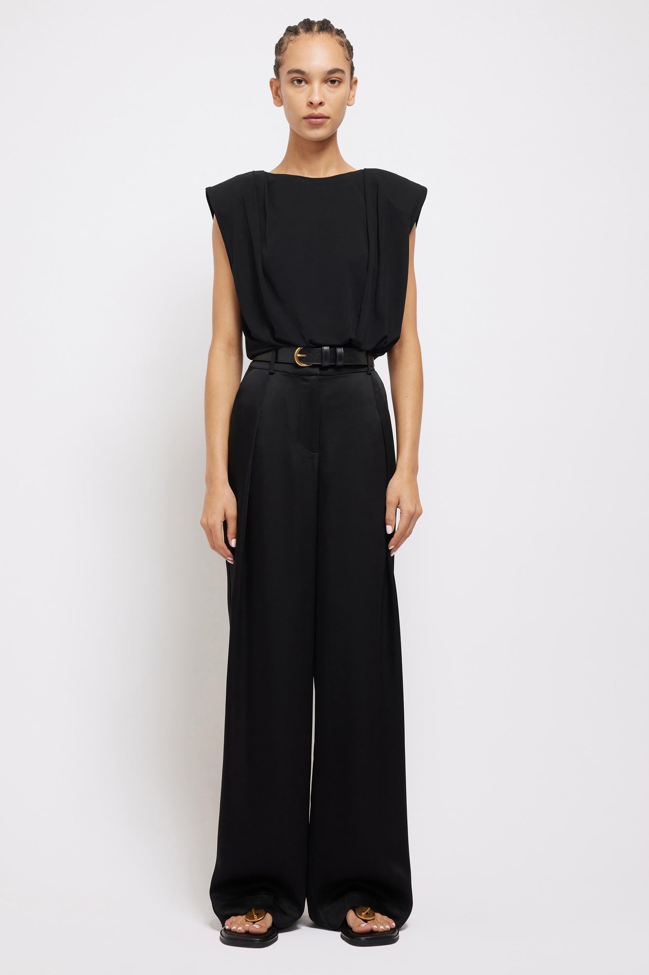 Black wide-leg pants with high waist and straight cut, styled with black belt.