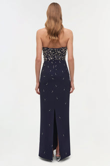Navy strapless gown with crystal embellishments on bodice and crescent moon beading throughout skirt, featuring a front slit.