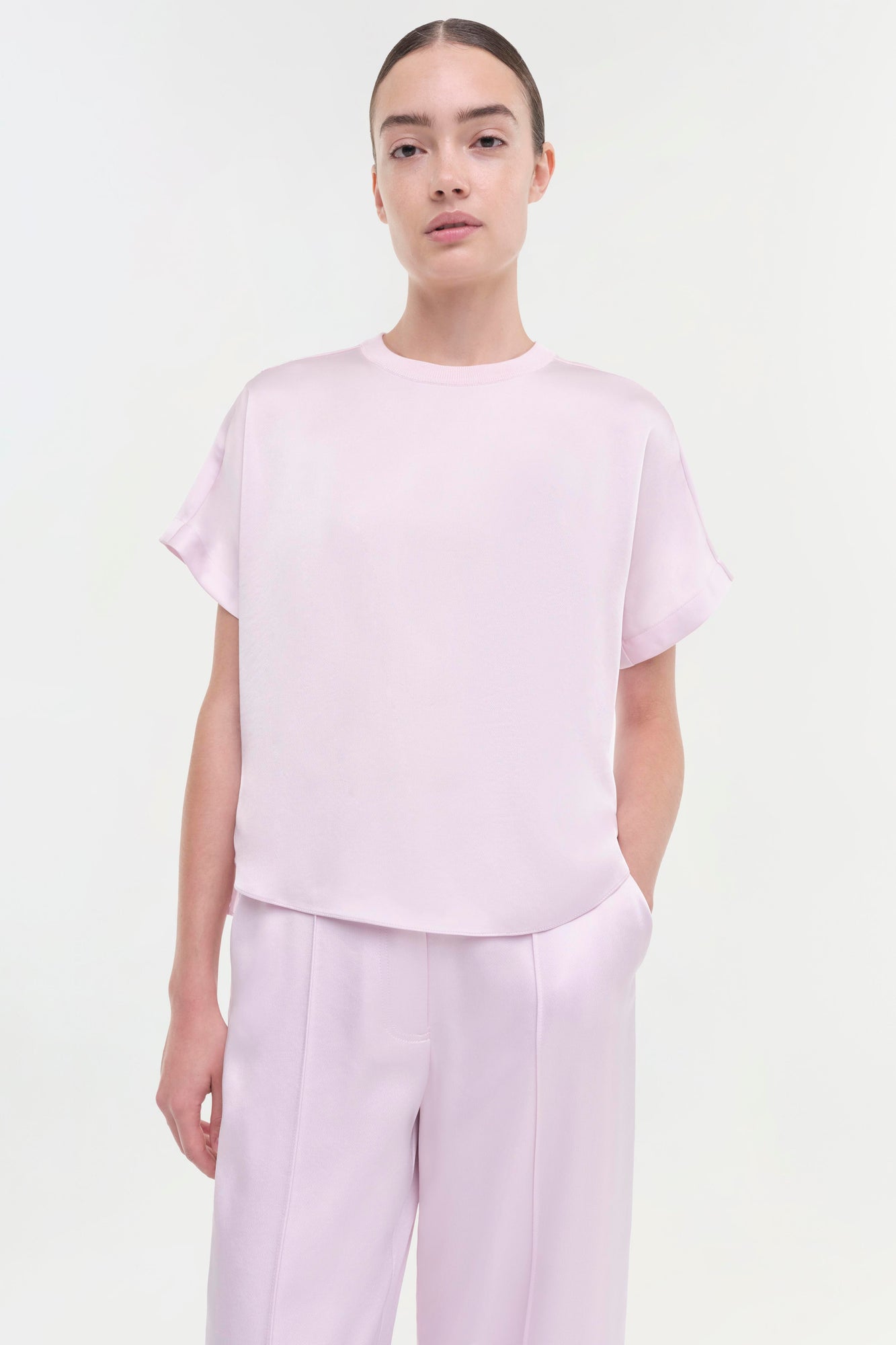 Woman wearing light pink short-sleeve t-shirt and high-waisted straight-leg pants in matching light pink.