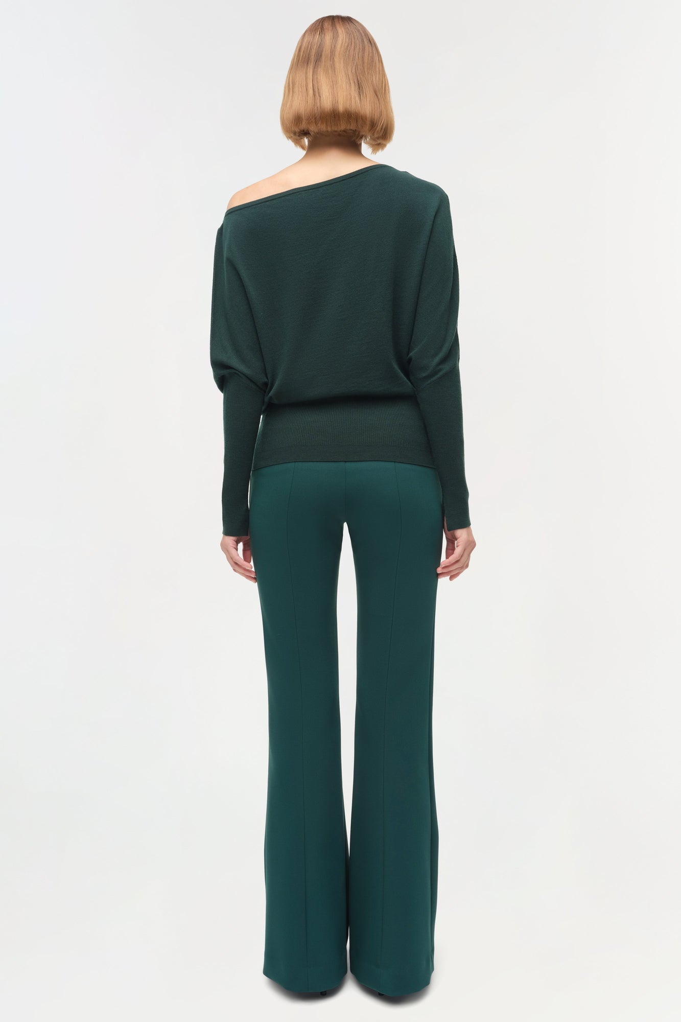 Dark teal off-shoulder sweater with long sleeves and ribbed waistband, shown from back view on model.