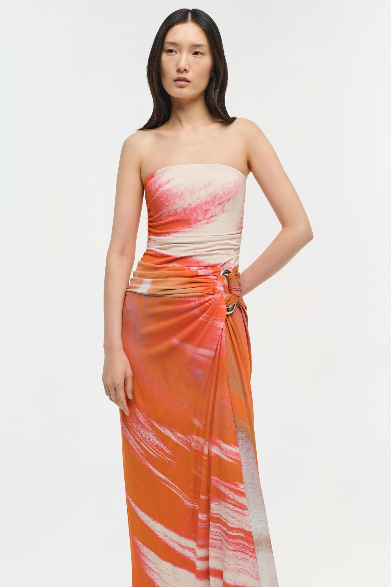 Strapless jersey gown with cream and orange watercolor print, ruched waist detail, and draped skirt.