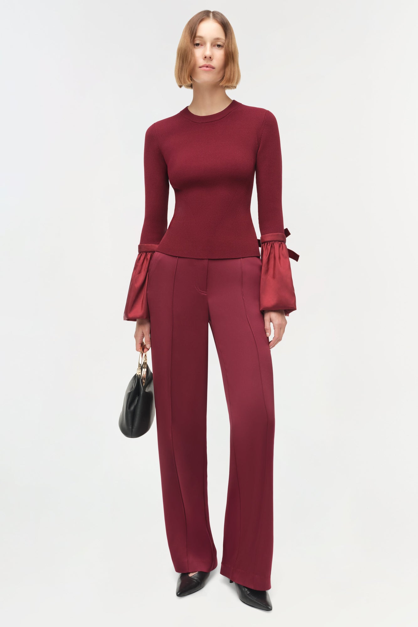 Woman wearing burgundy ribbed knit top with puffed taffeta sleeves and matching wide-leg trousers.