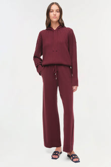 Woman wearing burgundy cable-knit hoodie and wide-leg drawstring pants with slide sandals.