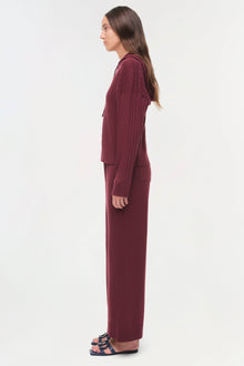 Woman wearing burgundy quilted long-sleeve top and matching straight-leg pants with side pockets, shown in profile.