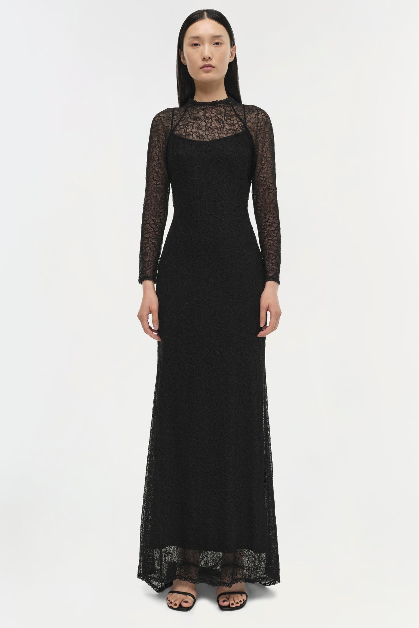 Black lace long-sleeved gown with sheer lace panels and fitted silhouette on model.