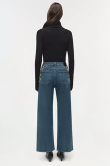 Blue denim crop jeans with embellished pocket details, worn with black turtleneck and heels.