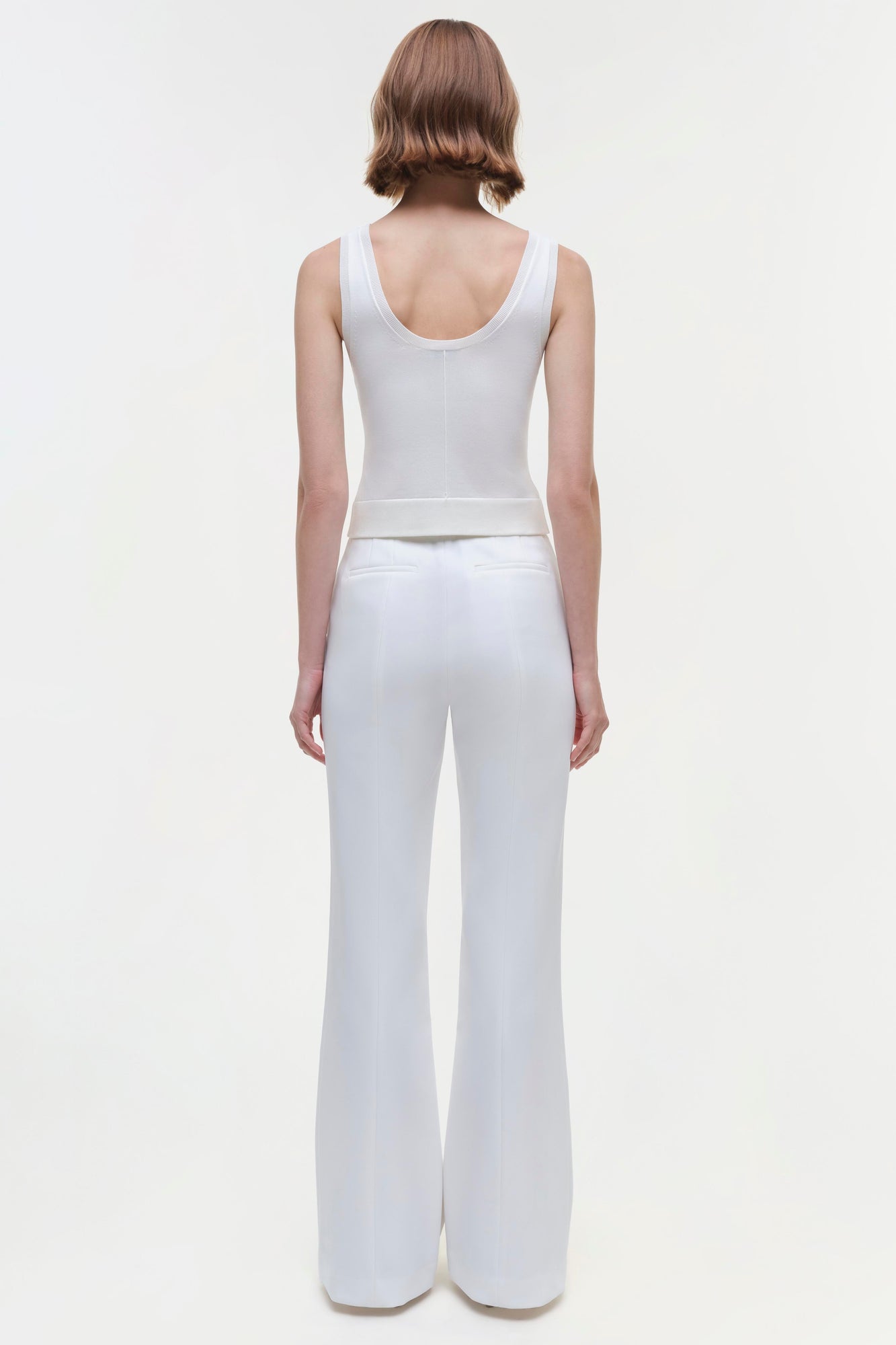 White sleeveless tank top with scoop neckline, shown from back on model wearing matching white flared pants.