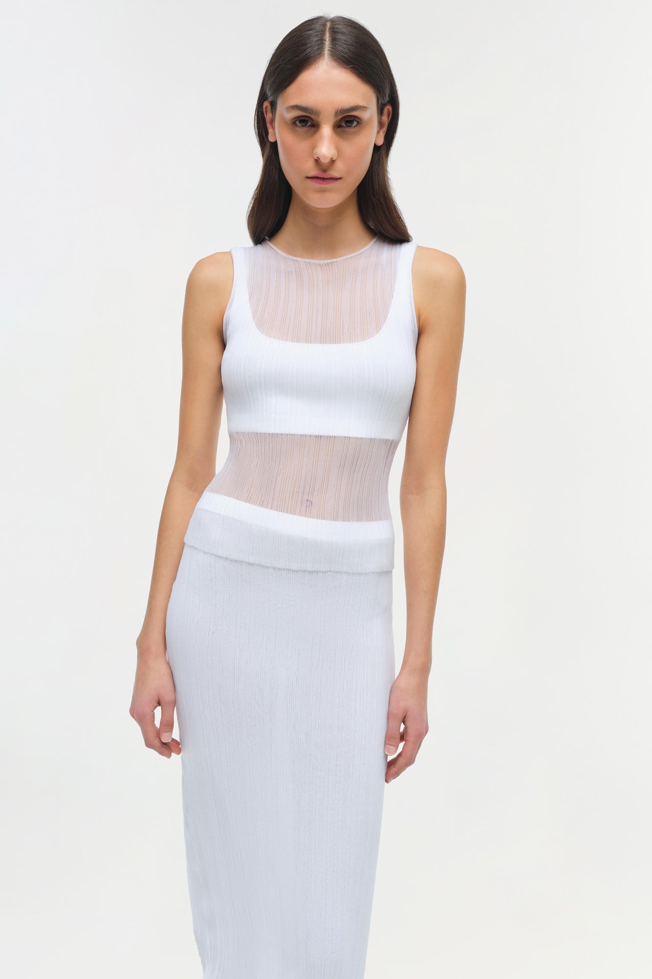 Woman wearing white ribbed sleeveless tank top with sheer mesh panels at neckline and midriff.