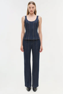 Woman wearing dark blue denim tank top and matching wide-leg trousers with vertical topstitching detail.