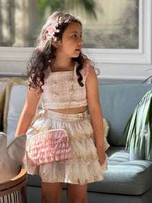 Girl wearing dusty pink organza ruffle handbag as a crossbody, featuring tiered ruffle detailing and gold metal frame