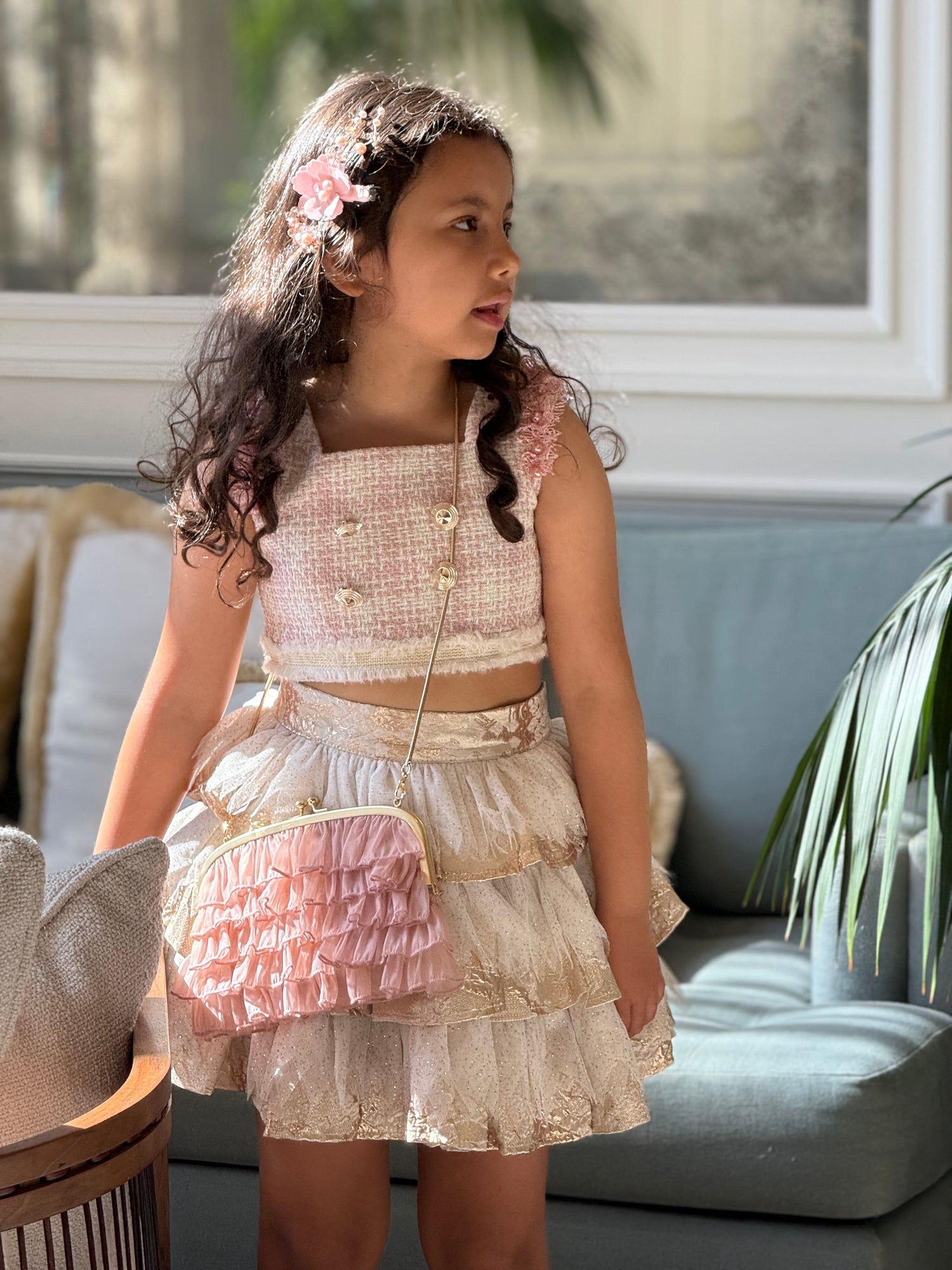 Girl wearing dusty pink organza ruffle handbag as a crossbody, featuring tiered ruffle detailing and gold metal frame