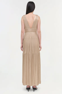 Beige sleeveless pleated gown with deep V-back and tiered skirt, shown from back view.
