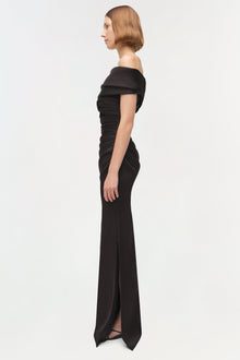 Woman wearing black off-shoulder gown with draped bodice and high slit, shown in profile view.