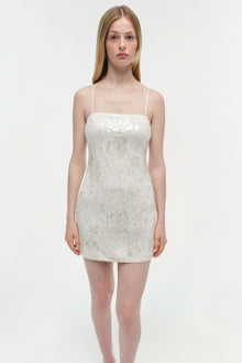 White sequined mini dress with thin straps and straight neckline on model.