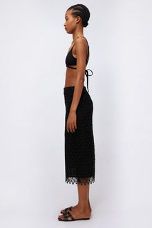 Black midi skirt with textured fabric and geometric lace trim at hem, worn with drawstring waist detail.