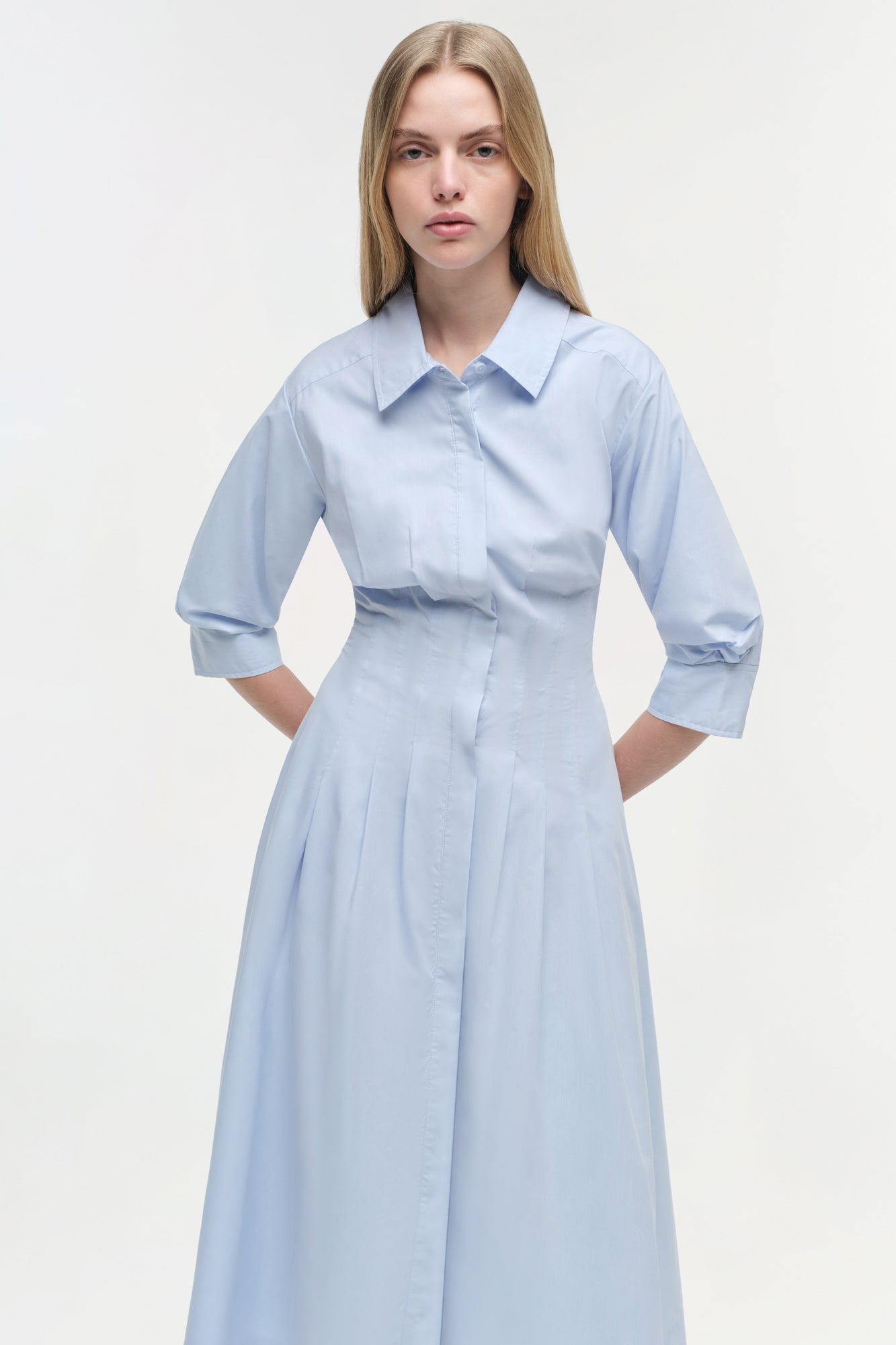 Light blue cotton midi dress with collared neckline, three-quarter sleeves, button front, and pleated skirt.