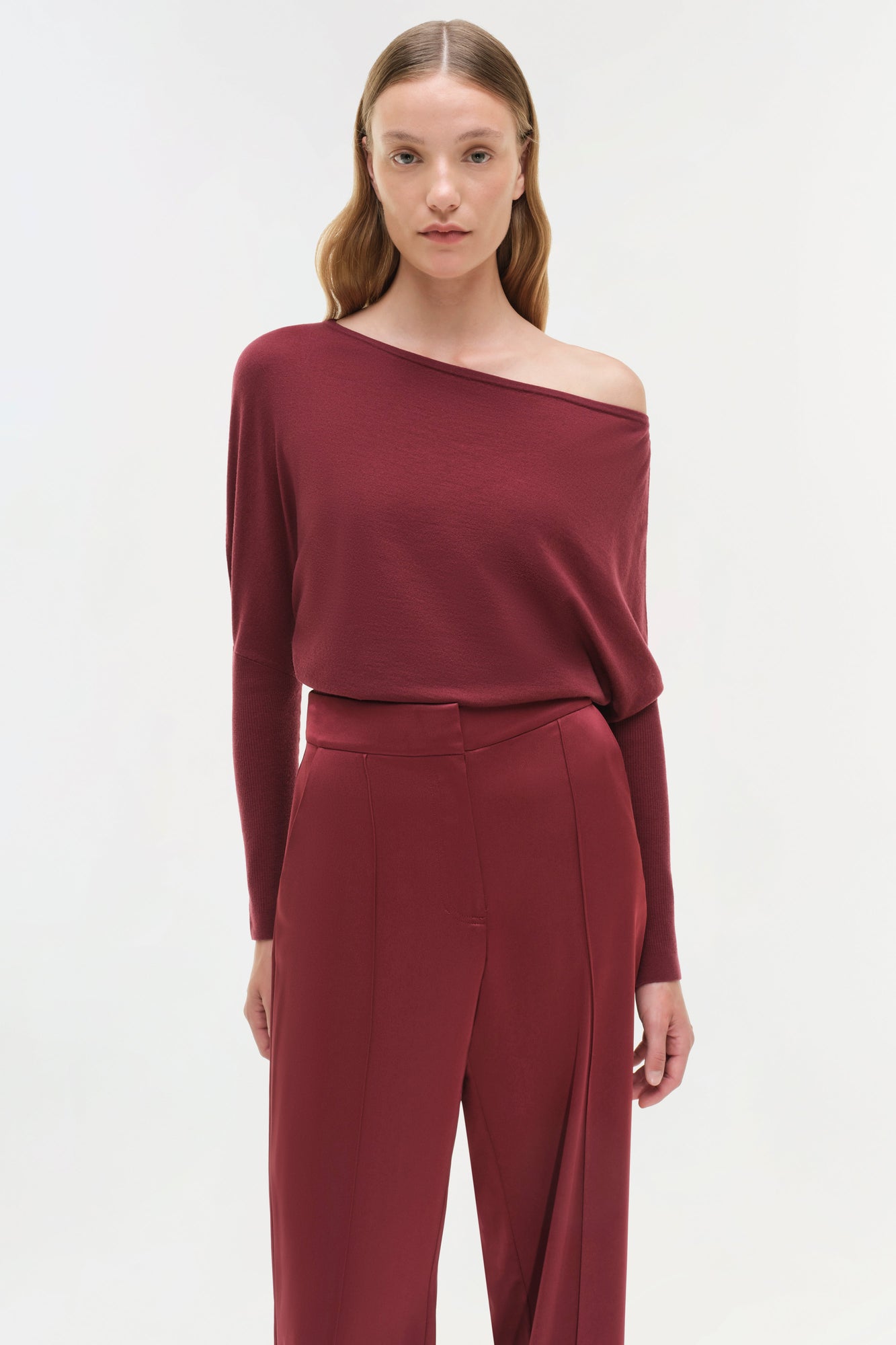 Woman wearing burgundy off-shoulder long-sleeve top and burgundy wide-leg satin pants.
