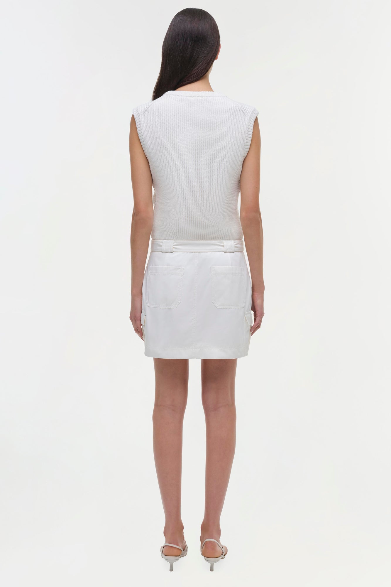 White sleeveless ribbed top with white denim skirt featuring back pockets, shown from behind.