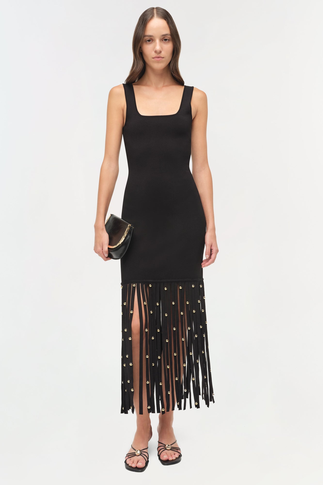 Black sleeveless midi dress with square neckline and fringed hem adorned with gold studs.