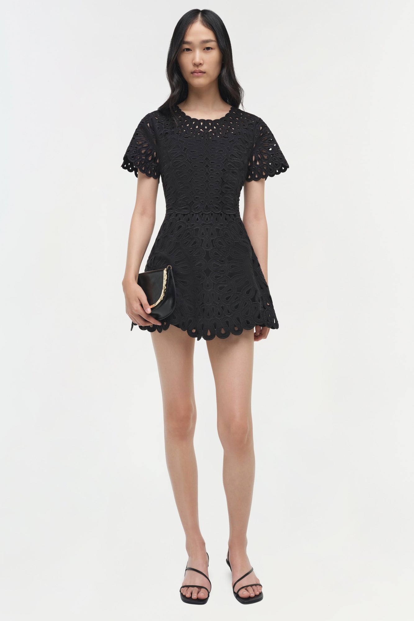 Black mini dress with eyelet embroidery, scalloped hem, and short flutter sleeves.