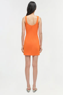 Woman wearing orange sleeveless mini dress with scoop back, shown from behind.