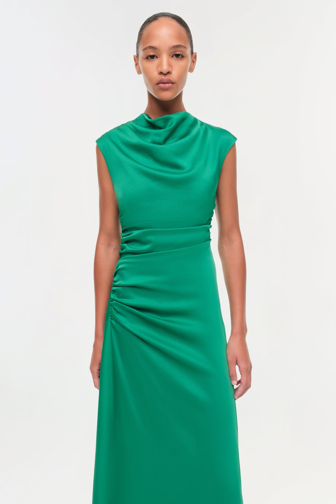 Emerald green satin midi dress with draped neckline, ruched waist, and sleeveless design.