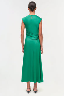 Woman wearing a sleeveless emerald green satin midi dress with ruched draping at the waist, shown from back view.